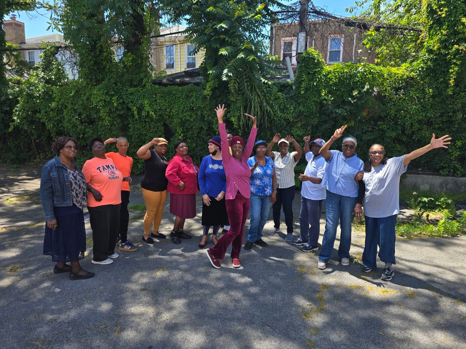 A joyful community group outdoors raising their hands together