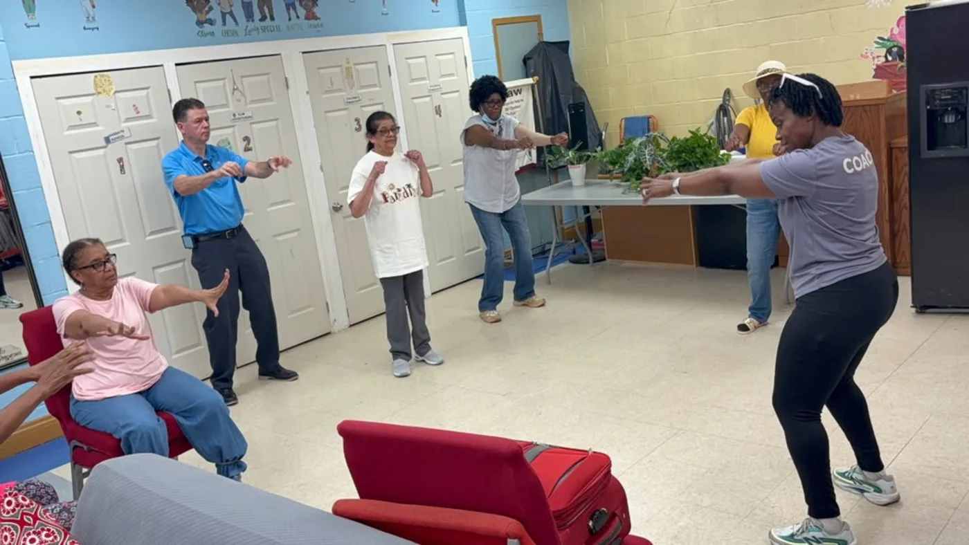 A coach leads seated and standing participants through an accessible movement sequence