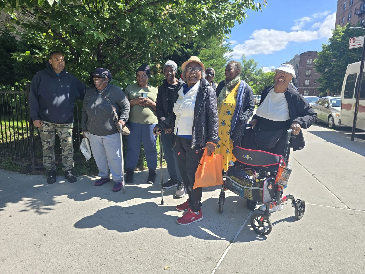 A mixed-ability community wellness group gathered outdoors, including participants using canes and a rollator